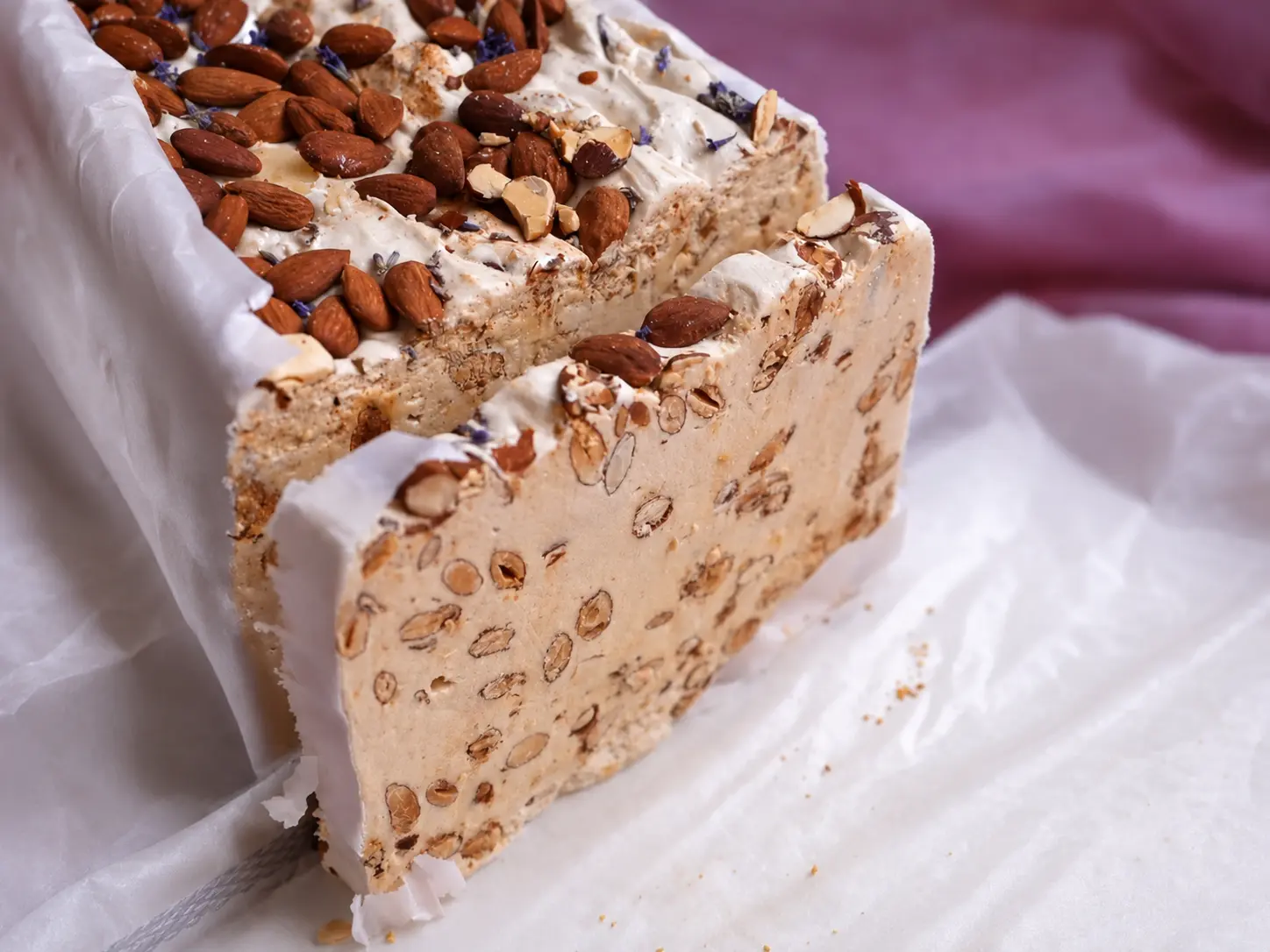 Gros plan sur un nougat artisanal d'Alsace au miel français, garni d'amandes, fabriqué par Bisch de Bruche et sélectionné par Trésor de la Nature.