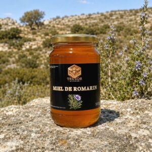 Miel de romarin d’Espagne – Trésor de la Nature Pot de miel de romarin d’Espagne Trésor de la Nature, présenté au cœur d’un paysage méditerranéen où pousse le romarin.