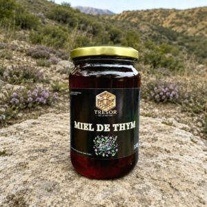 Miel de thym d’Espagne – Trésor de la Nature Pot de miel de thym d’Espagne Trésor de la Nature, présenté dans un paysage méditerranéen où pousse le thym sauvage.